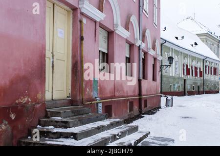 Das Bild von Eingang und Stufen mit gelber Tür des alten Hauses in der Innenstadt von Brasov, Rumänien im Winter. Stockfoto