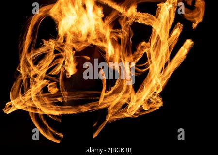 Brandlinien auf schwarzem Hintergrund. Flammen im Dunkeln. Schießen Sie mit langer Verschlusszeit eine Feuerdrehung. Stockfoto