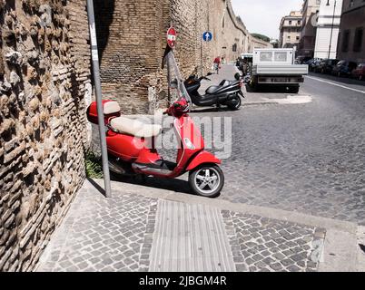 Red Vespa Roller in der Innenstadt. Vespa Bike wird in einigen Szenen in 'Roman Holiday' verwendet, einem Film aus dem Jahr 1953, der in den Cinecittà Studios und in der Umgebung von Rom gedreht wurde. Stockfoto