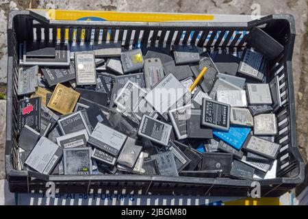 Belgrad, Serbien - 14. Mai 2022: Ein großer Haufen gebrauchter Handy-Batterien für das Recycling in Crate. Stockfoto