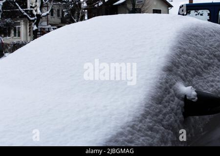Nahaufnahme des Autos in der Wintersaison, Bukarest, Rumänien. Schnee stapelte sich auf dem geparkten Auto. Stockfoto
