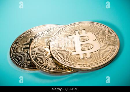 Die Nahaufnahme von drei Goldbitcoins im schlichten Hintergrund. Stockfoto