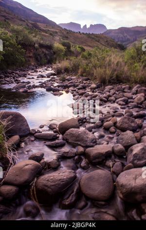 Ruhiger Blick über den Cowl Fork River in der Abenddämmerung, mit dem Mönchs Cowl Peak im Hintergrund, Drakensberg Mountains, Südafrika Stockfoto