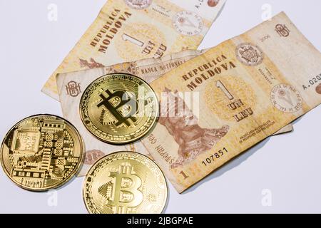 Nahaufnahme der Banknoten des moldawischen Leu (mdl) mit Bitcoins auf weißem Hintergrund. Stockfoto