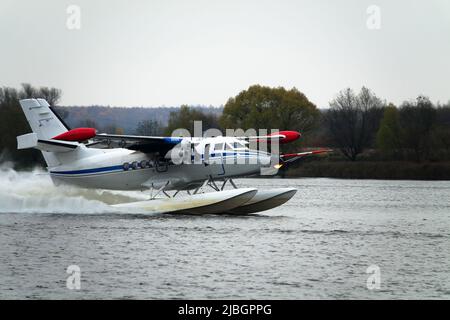 Das zweimotorige Wasserflugzeug ein Wasserflugzeug steigt aus dem Wasser, aus dem Waldsee, dem nördlichen Land auf. Wasserflugzeug Stockfoto