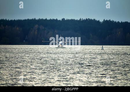 Das zweimotorige Wasserflugzeug ein Wasserflugzeug steigt aus dem Wasser, aus dem Waldsee, dem nördlichen Land auf. Wasserflugzeug Stockfoto