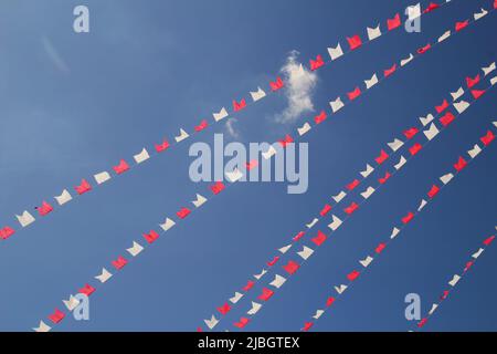 Pirenópolis, Goiás, Brasilien – 05. Juni 2022: Einige Linien von Fahnen in weiß und rot, hängen mit blauem Himmel im Hintergrund. Stockfoto