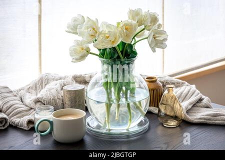 Home Komposition mit einem Bouquet aus Tulpen in einer Glasvase und Kerzen. Stockfoto