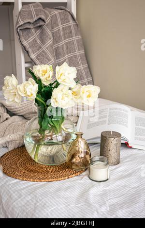 Home Komposition mit einem Bouquet aus Tulpen in einer Glasvase und Kerzen. Stockfoto