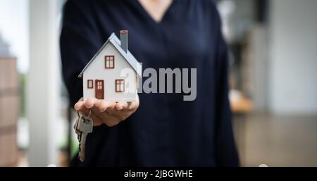 Immobilienmakler, der Schlüsselhaus und Modell übergibt, das Versicherungskonzept vermietet und verkauft. Stockfoto