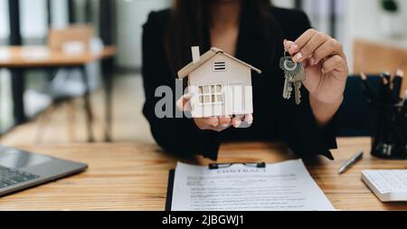 Immobilienmakler, der Schlüsselhaus und Modell übergibt, das Versicherungskonzept vermietet und verkauft. Stockfoto