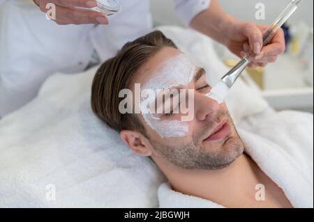 Nahaufnahme eines Mannes mit einer feuchtigkeitsspendenden Maske im Gesicht Stockfoto