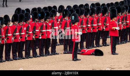 Der Soldat in Uniform wird während der Probe der Trooping the Colour Militärparade ohnmächtig und markiert damit das Platinum Jubiläum von Königin Elizabeth. Stockfoto