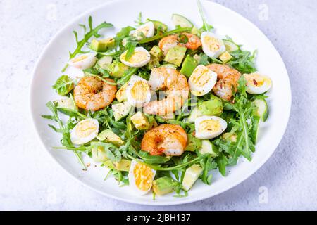 Salat mit Garnelen, Avocado, Gurken, Wachteleiern und Rucola. Traditionelle mediterrane Küche. Nahaufnahme. Stockfoto