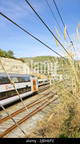 Gleise und Fahrbahn hinter dem Drahtzaun in El Garraf, Barcelona, Katalonien, Spanien, Europa Stockfoto