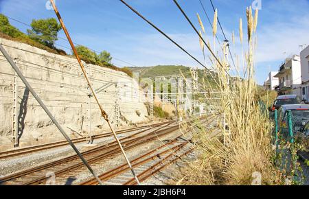 Gleise und Fahrbahn hinter dem Drahtzaun in El Garraf, Barcelona, Katalonien, Spanien, Europa Stockfoto