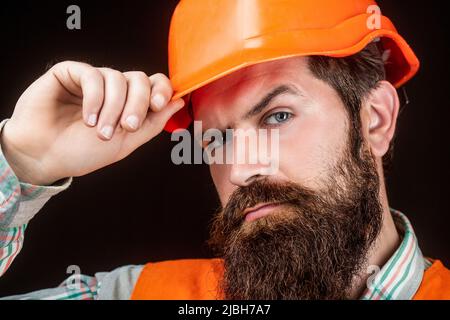 Baumeister, Industrie. Bärtiger Arbeiter mit Bart beim Bau von Helm oder Hut. Porträtbauer, Bauingenieur arbeitet. Baumeister in Harthut Stockfoto
