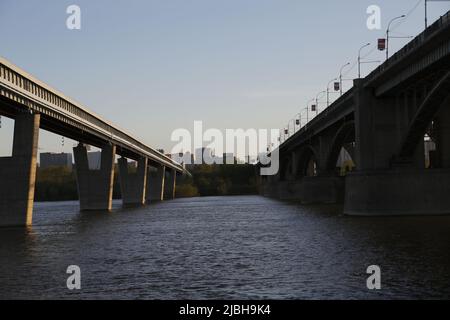 Blick zwischen den Brücken über den ob in Nowosibirsk; Oktoberbrücke / Kommunalbrücke (links) und längste überdachte U-Bahnbrücke der Welt (rechts) Stockfoto