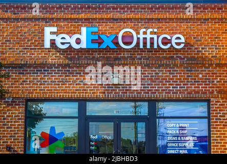 FedEx Office Außenfassade-Marke und Logo-Beschilderung in weißen und blauen Buchstaben auf einem rötlichen Backsteingebäude über reflektierenden Fenstern und Türen. Stockfoto