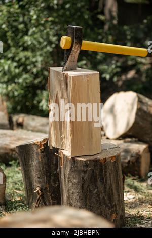 Eine Spaltpickel ragt in einem Baumstamm hervor. Brennholz zum Anzünden des Ofens. Landwirtschaft, Stockfoto