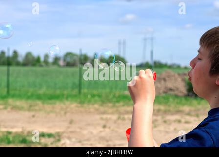 Das Kind bläst Seifenblasen in die Natur. Stockfoto