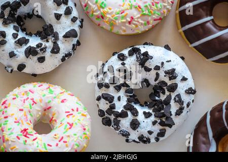 Flach legen Bild von Donut mit weißer Glasur und schwarzen Cookies amids anderen verschiedenen Donuts Stockfoto