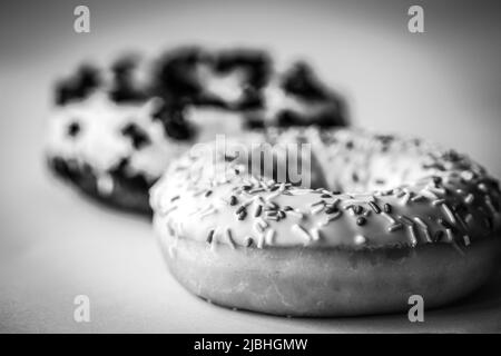 Nahaufnahme eines Ringdonuts mit weißer Glasur und hunderttausenden Schwarz-Weiß-Bildern Stockfoto