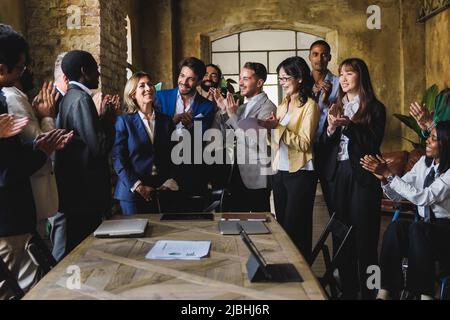 Verschiedene Geschäftsleute feiern gemeinsam im Bankbüro – Fokus auf das Gesicht des Mittelmanns Stockfoto