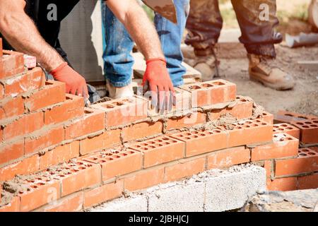 Maurer arbeiten an einer gebogenen Wand Stockfoto