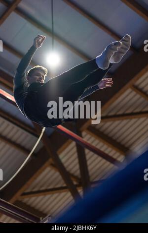 Junger Mann, der im Trampolin springt. Vertikaler und niedriger Winkel Stockfoto