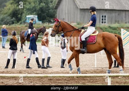 Junge Reiterin Mädchen auf dem Lorbeerpferd vor der Dressurprüfung. Pferdesport Wettbewerb Konzept Hintergrund. Stockfoto