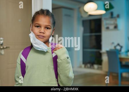 Vorderansicht Porträt eines afroamerikanischen Mädchens mit Maske und Rucksack, das im September zur Schule zurückgeht, Platz kopieren Stockfoto