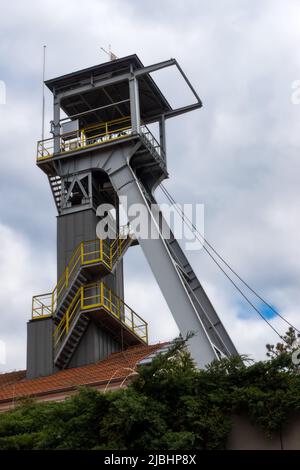 Blick auf den Minenschachtlift rollt gegen den bewölkten Himmel. Das Objekt wird von natürlichem Sonnenlicht beleuchtet, das durch die Wolken zieht Stockfoto