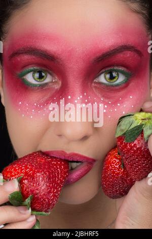 Fantasy Make-up Portrait einer Frau Erdbeerauge und rote Lippen auf schwarzem Hintergrund Stockfoto