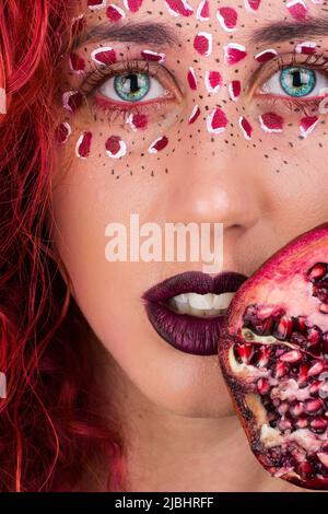 Fantasy Make-up Porträt einer Frau mit Granatapfel, blauen Augen und violetten Lippen Stockfoto