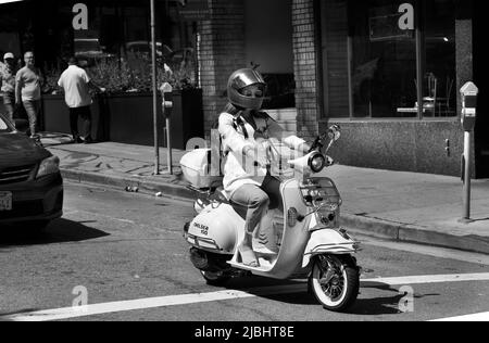 Eine Frau auf einem BMS Chelsea 150 Roller hält an einer Ampel in San Fancisco, Kalifornien, inne. Stockfoto