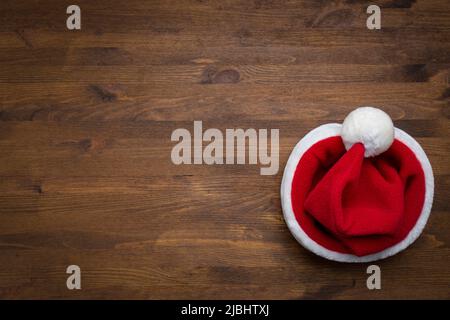 Weihnachtsmann Hut auf einem hölzernen Hintergrund. Weihnachten, Neujahr Stockfoto