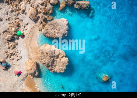 Luftaufnahme des blauen Meeres, Strand mit Sonnenschirmen, Felsen im Wasser Stockfoto