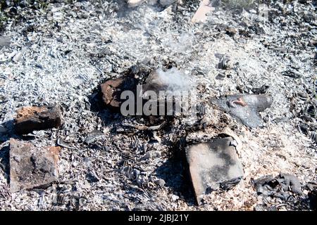 Lufttrockner Blick über brennendes trockenes Gras und Rauch im Feld. Flamme und offenes Feuer. Draufsicht Schwarzer Asche aus gegerbtem Gras, aufsteigender weißer Rauch und Yello Stockfoto