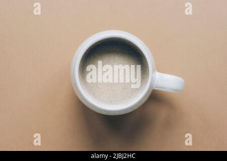 Eine Tasse Kaffee mit Schaum auf neutralem Hintergrund. Draufsicht, flach liegend. Stockfoto