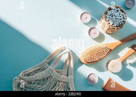 Naturkosmetik, Holzbürsten, Ohrreinigungsstäbe, Kerzen und Netzbeutel auf hellblauem Tisch mit harten Schatten. Zero Waste Konzept. Draufsicht, flach Stockfoto