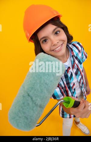 Maler in der Werkstatt. Renovierung und Reparatur. Teen Mädchen im Helm mit Pinsel malen. Kind in Hut. Kinderbaumeister Maler auf Baustelle. Stockfoto