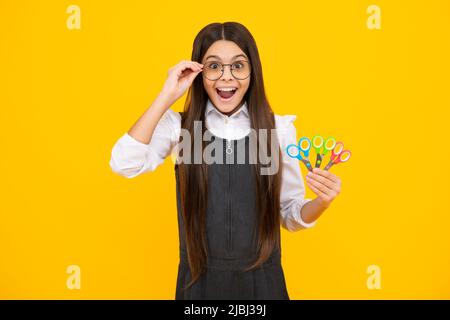 Kinder Kreativität, Kunst und Handwerk. Teenagermädchen mit Schere, isoliert auf gelbem Hintergrund. Stockfoto