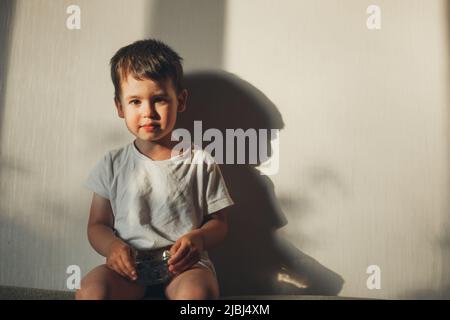 Kind hält eine Schale mit Heidelbeeren Bio-Produkt, sitzt auf dem Sofa zu Hause. Stockfoto
