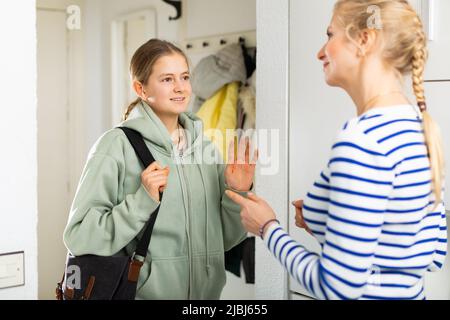 Tochter sagt Auf Wiedersehen Mutter in der Eingangshalle der Wohnung Stockfoto