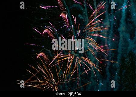 Schönes festliches Feuerwerk, goldrosa in der Farbe, mit einem bläulichen Dunst, vor dem Hintergrund des Nachthimmels. Hochwertige Fotos Stockfoto