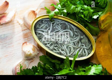 Eingelegte Aale in offener Dose mit Knoblauch am Tisch Stockfoto