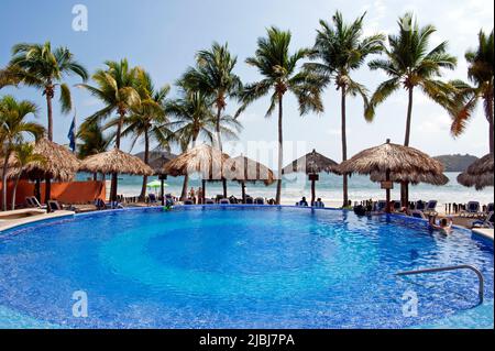 Strandhotel mit Swimmingpool und Palmen in Zihuatanejo, Mexiko Stockfoto