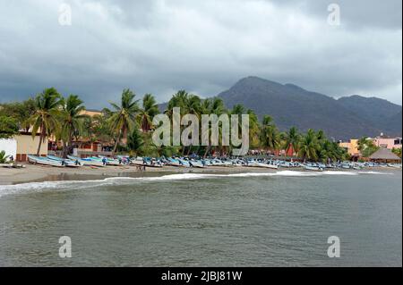 Panoramablick auf Fischerboote am Strand mit Palmen und Hügeln in Zihuatanejo, Mexiko Stockfoto