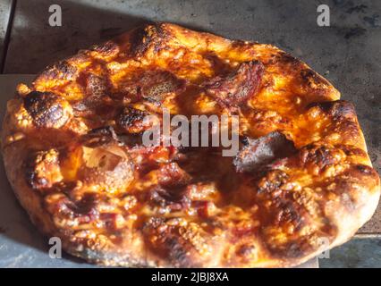 Hausgemachte italienische Pizza mit natürlicher Gärung, verschiedene Geschmacksrichtungen, darunter Pastrami, Speck und Pulled Pork, Pizza-Konzept. Stockfoto